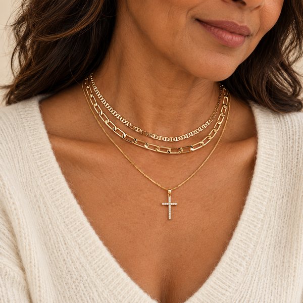 Layered gold necklaces with cross pendant on model