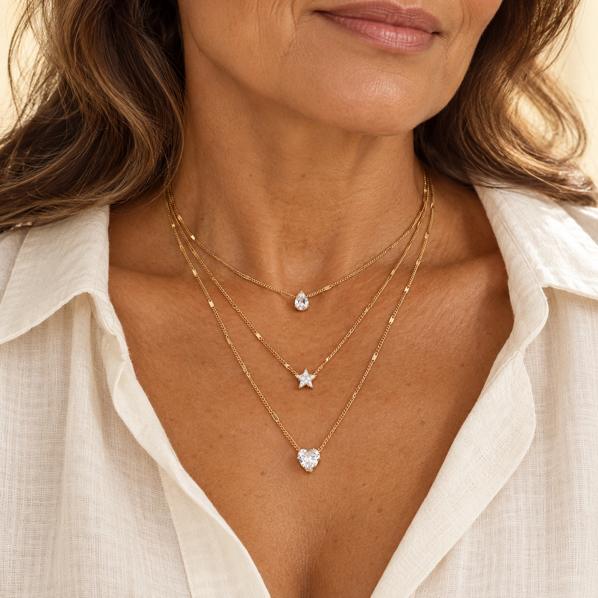 Layered gold necklaces with clear stone pendants on model