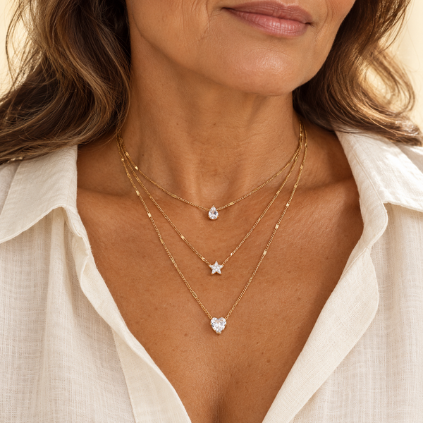 Layered gold necklaces with clear stone pendants on model