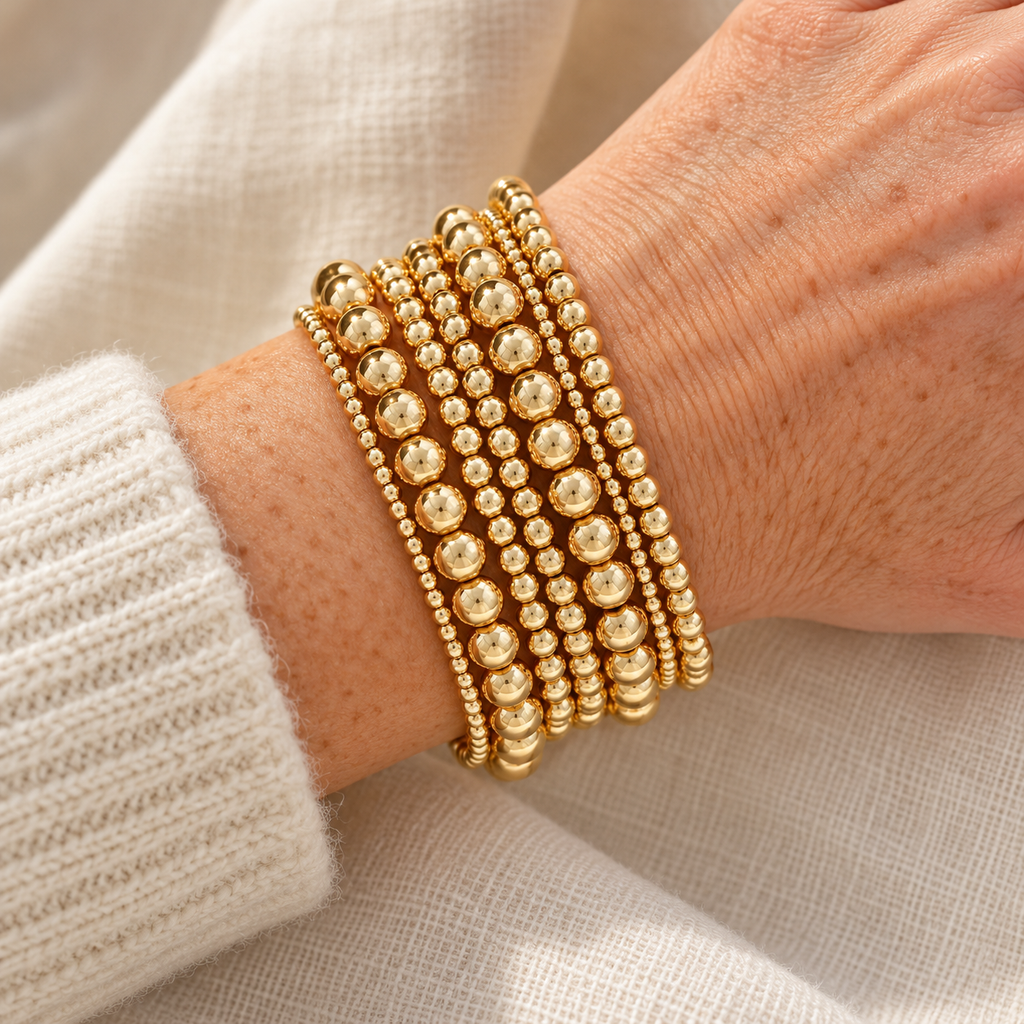 Seven-piece gold beaded bracelet stack on wrist