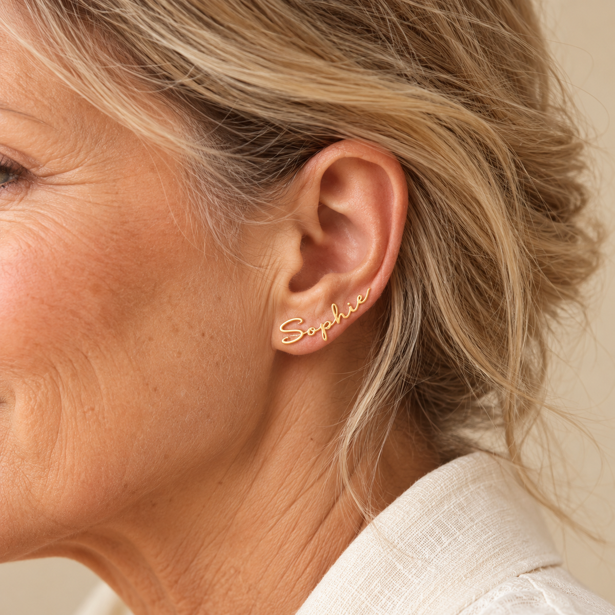 Gold personalised Sophie name earrings on mature model