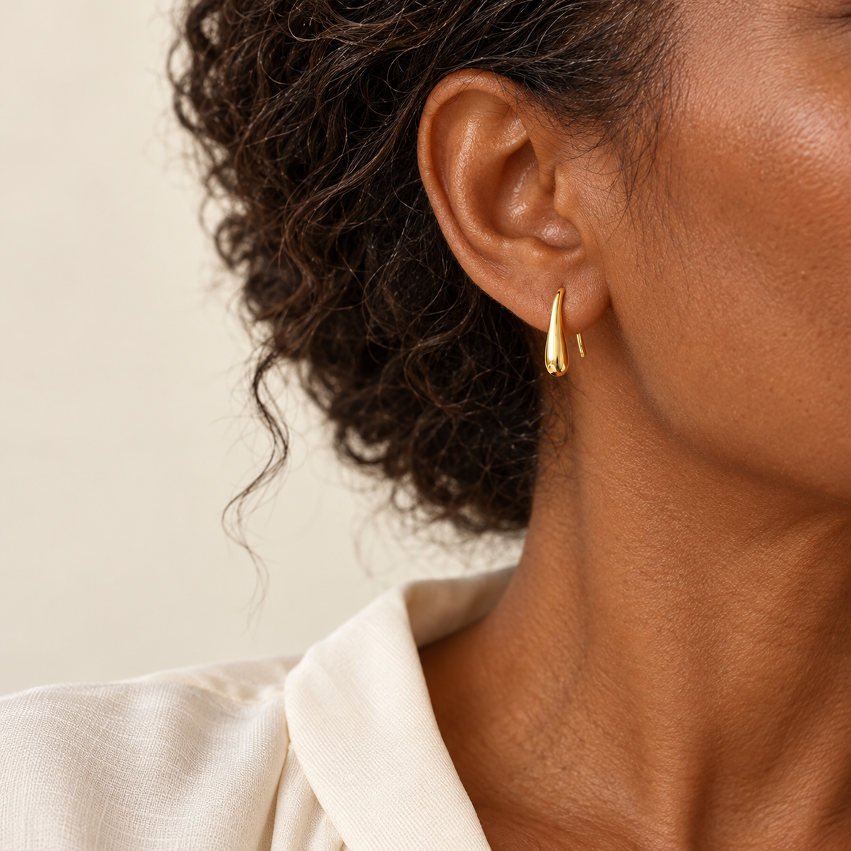 Gold droplet hook earrings on model