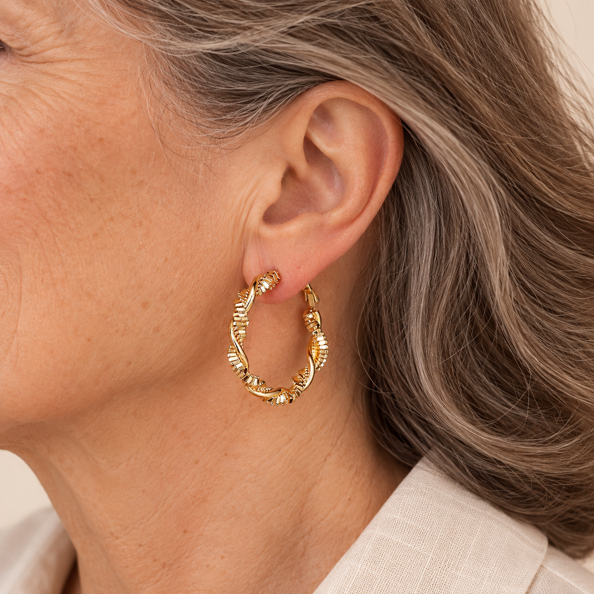 Gold textured spiral hoop earrings on mature model