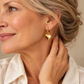 Gold heart drop hoop earrings on mature model