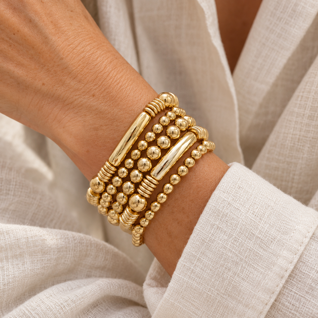 Five gold beaded bracelets on a woman’s wrist