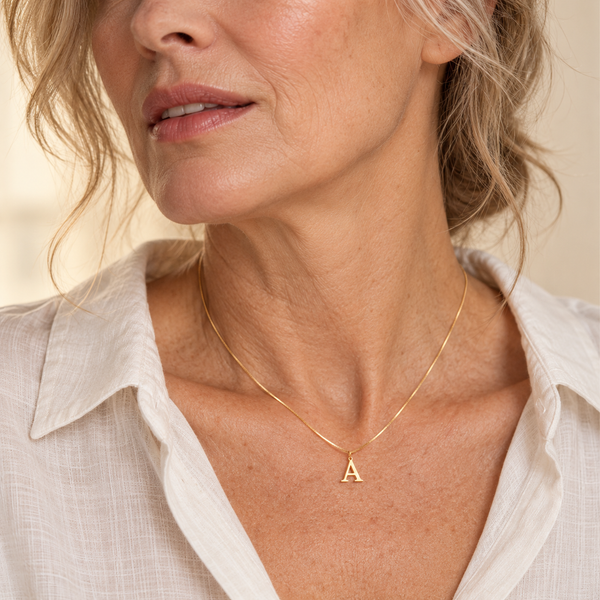 Fine gold serif A initial necklace on mature model