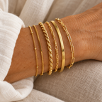 Six gold chain bracelets on a woman's wrist